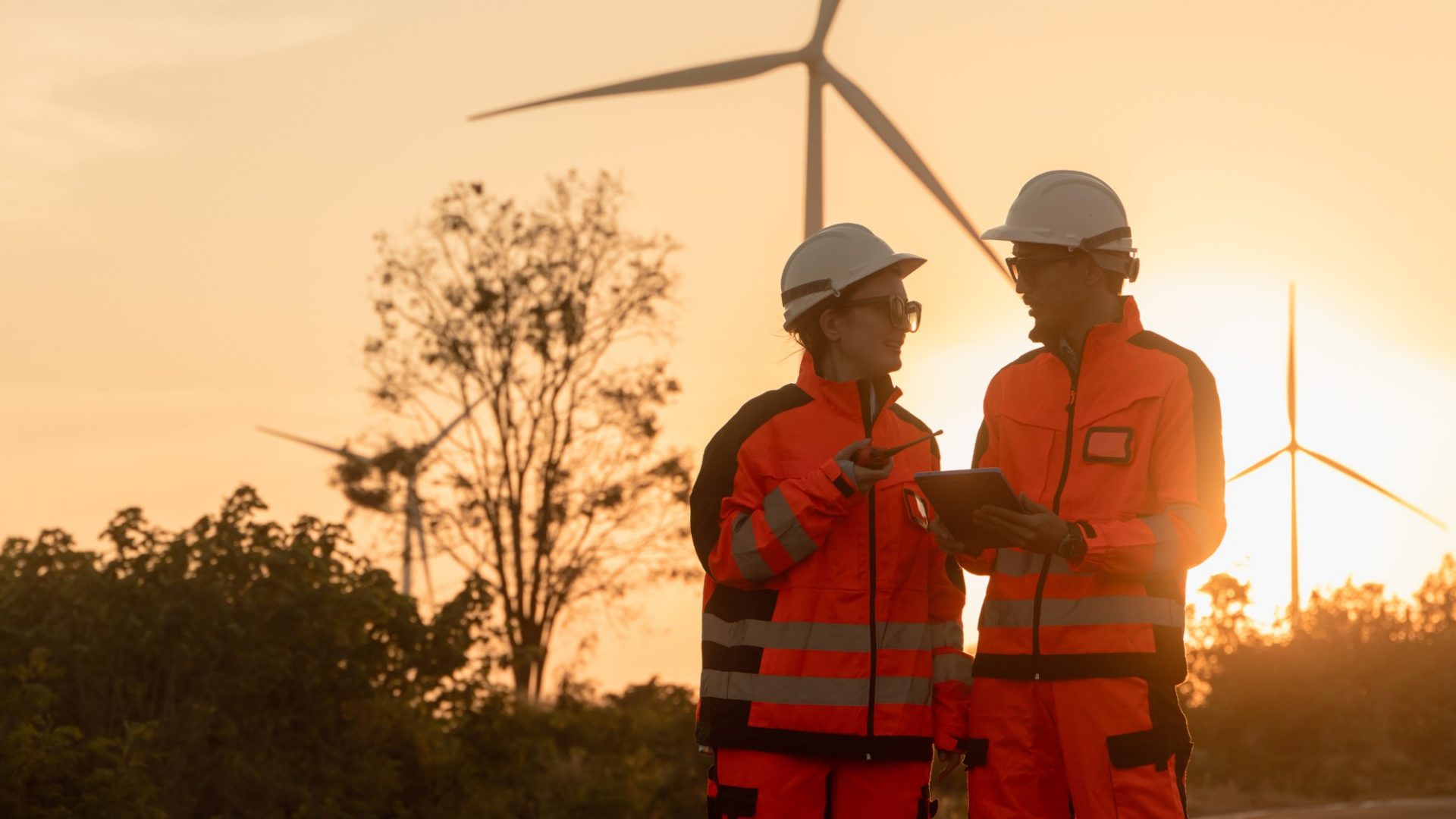 Mann und Frau bei der Arbeit an Windrädern in der Dämmerung